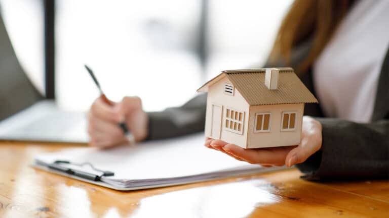 An accountant reviewing documents and recording assets and liabilities on a paper.
