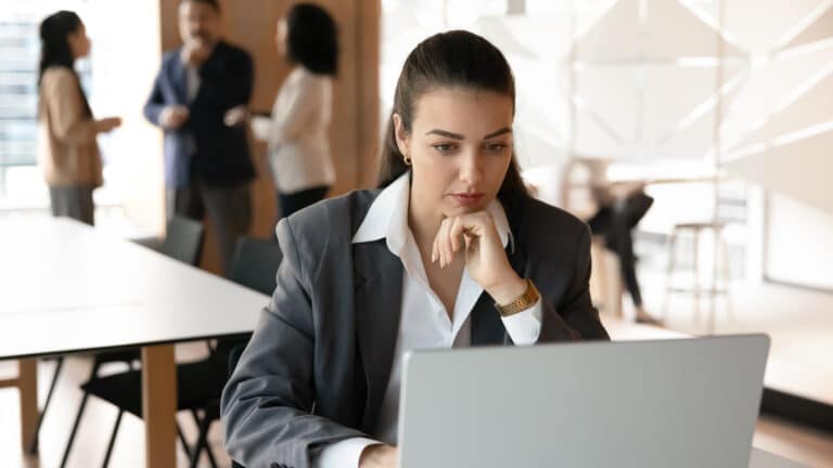 Business professional reviewing tax news and regulations on a laptop in a modern office.