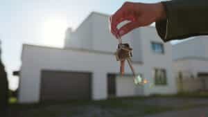 A hand holding house keys in front of a modern home, symbolizing real estate purchase and tax decisions in Croatia in 2026.