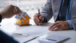 Business professionals reviewing real estate purchase documentation next to a model house, symbolizing property investment and tax planning in Croatia.